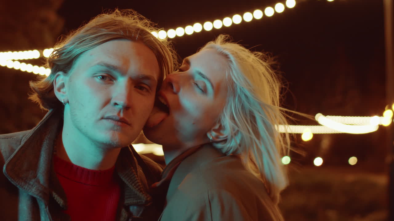 젊은 부부가 밤에 거리에서 카메라를 위해 포즈를 취하고 있습니다.