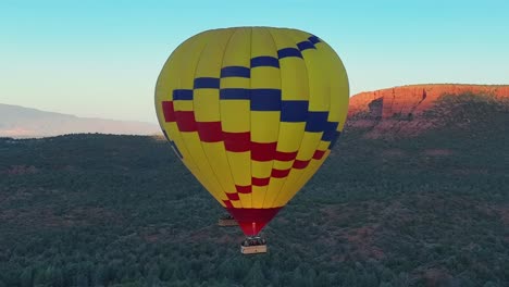 colorful hot air balloon rising in blue sky in sedona, arizona - aerial drone shot