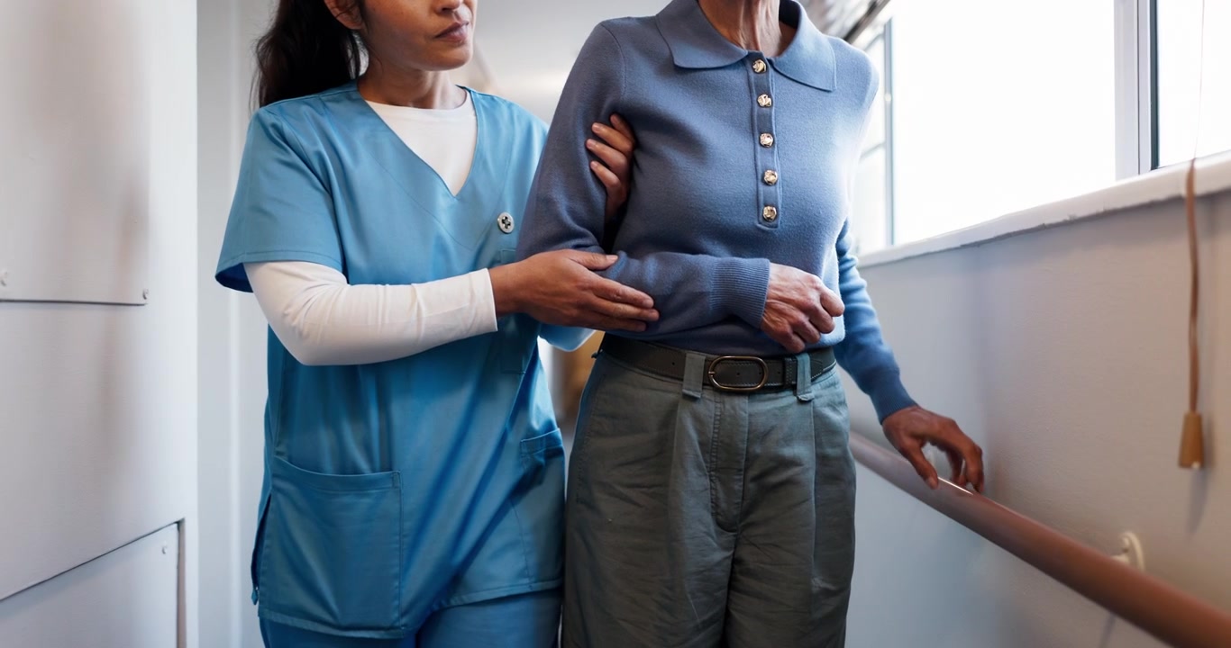 Nurse Assisting Elderly Patient Walking in Hospital Corridor