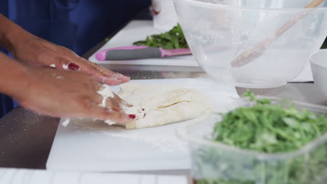 close up of woman working dough for dish in kitchen cookery class