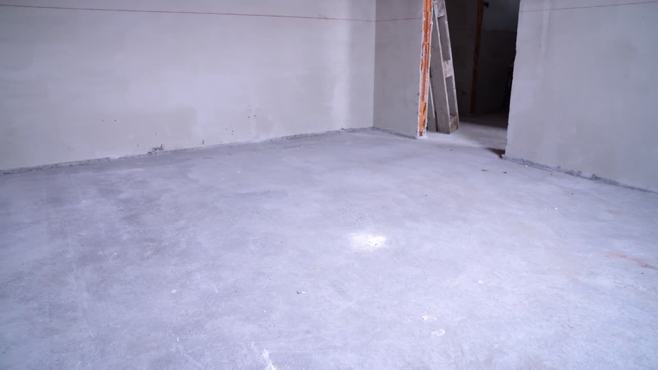 Empty unfinished room with concrete floor and electrical installations during renovation