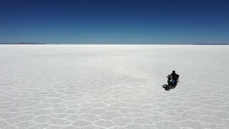 Hex-pattern-on-Uyuni-Salt-Flat,-motorcycle-rider-approaches-camera