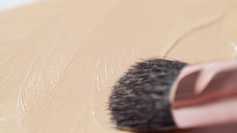 creando texturas mientras se cepilla de la izquierda a la derecha del marco, con una base de piel desnuda en una tabla blanca limpia utilizando un aplicador de pincel