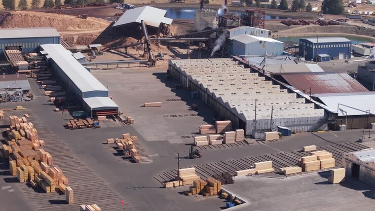 Industrial sawmill operation with lumber stacks and factory buildings
