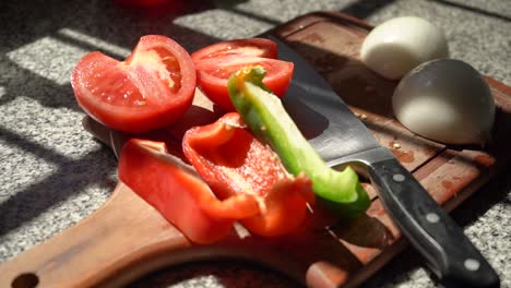 slices of tomato, onion, red and green bell peppers on a wooden chopping board