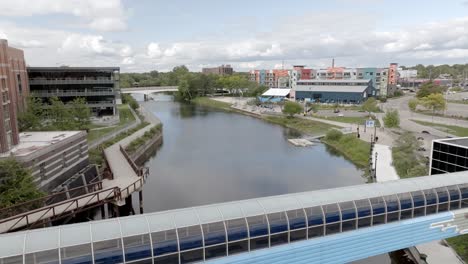 Pasarela-Peatonal-Sobre-Grand-River-En-El-Centro-De-Lansing,-Michigan,-Con-Video-De-Drones-Avanzando