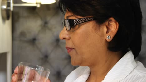 mature woman taking medicine with glass of water 4k