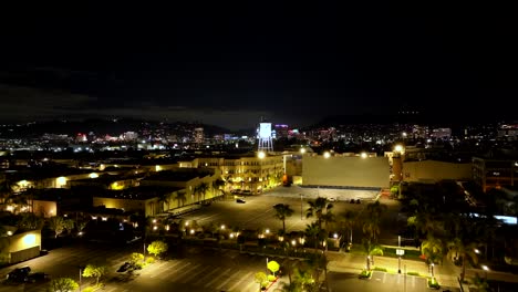 Night-time-aerial-view-rising-above-Paramount-pictures-illuminated-water-tower-movie-studio,-Los-Angeles