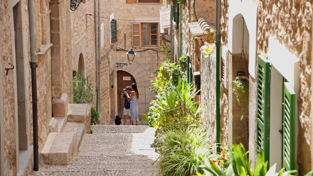 Una coppia sta scattando foto sul marciapiede a Valldemossa, il villaggio più alto di Maiorca