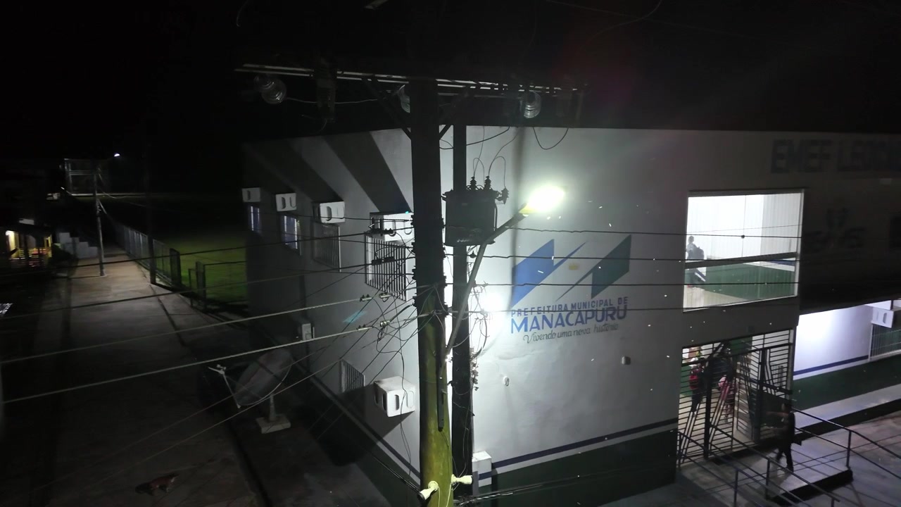 Street light mounted on a utility pole at night, illuminating an urban environment and helping to ensure public safety, captured in an Amazonian settlement, cinematic aerial views