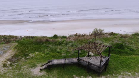 Aerial-video-of-a-wooden-structure-located-on-the-coast-with-the-beach-behind