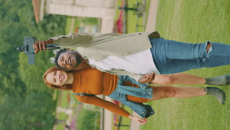 video vertical de una joven pareja viajando por la ciudad juntos vlogging a la cámara de video en el parque