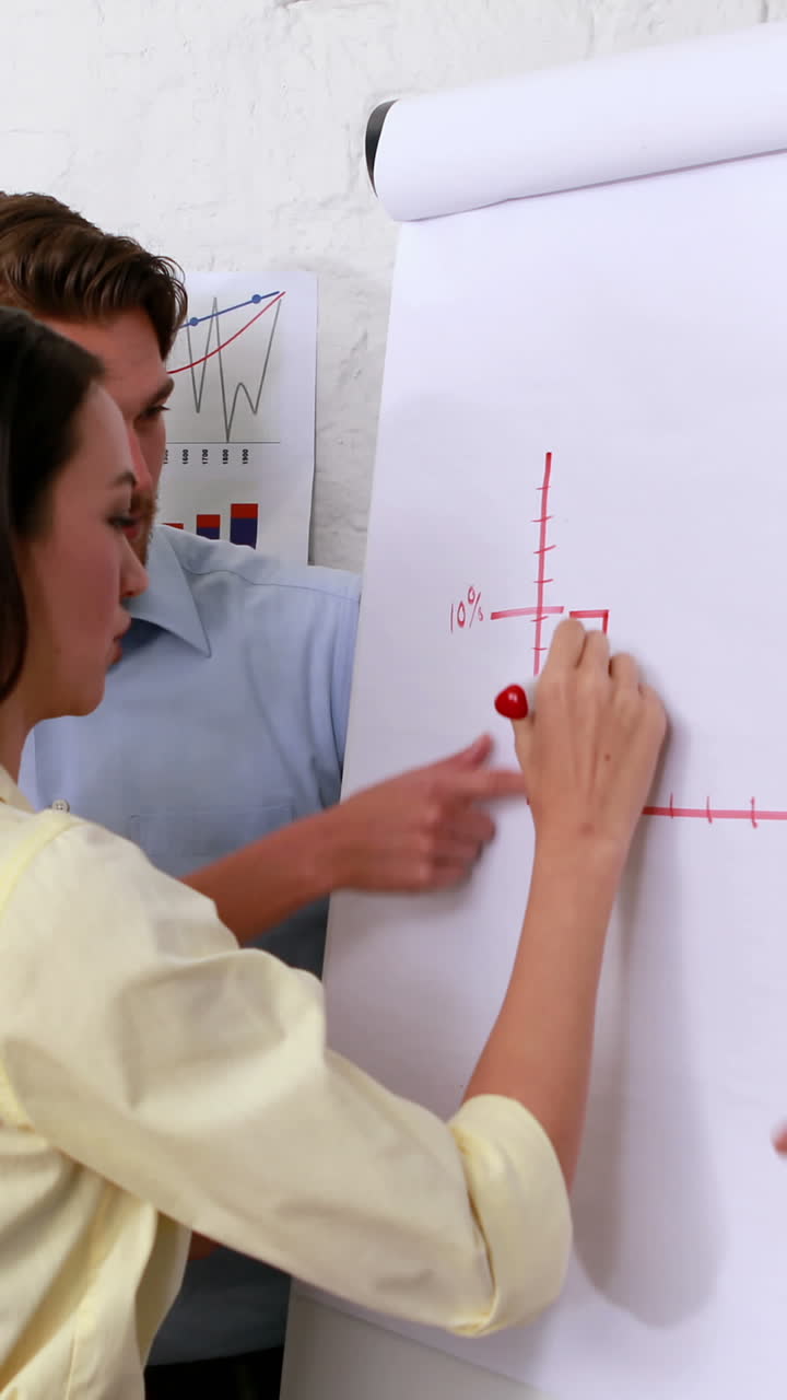 캐주얼 비즈니스 팀이 동료가 그래프를 그리는 것을 지켜보고 있습니다.