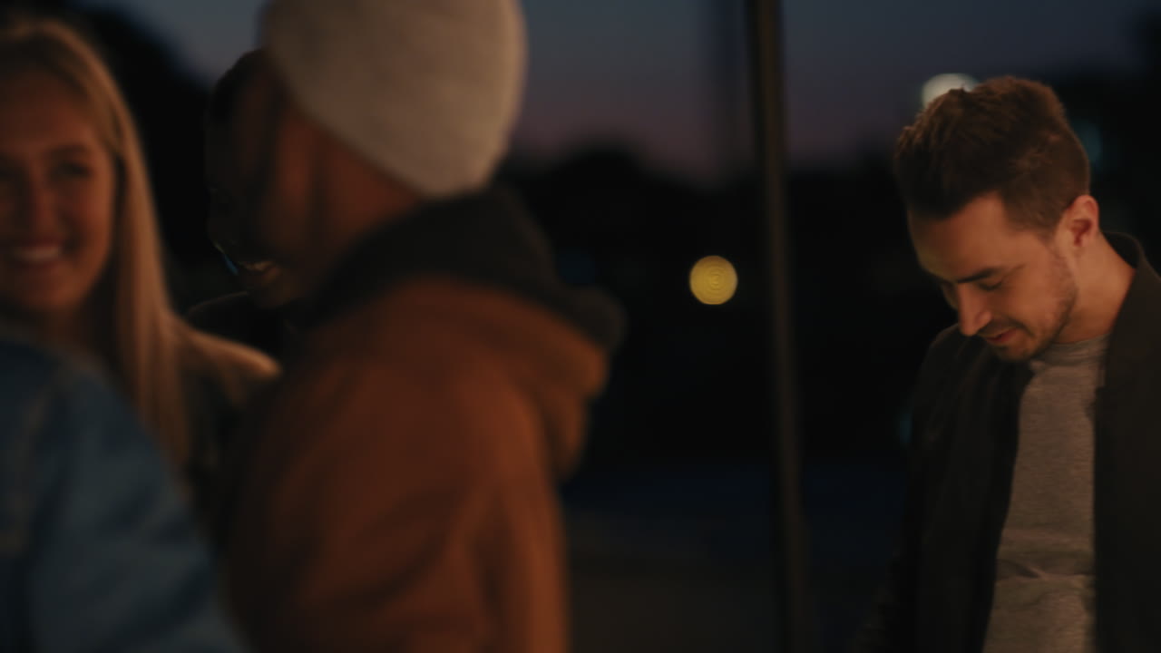 группа друзей наслаждается вечеринкой на крыше ночью антисоциальный мужчина пьет алкоголь выглядит скучно в выходные праздничный вечер