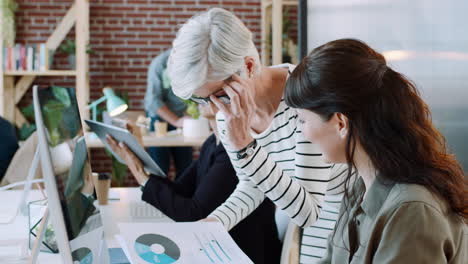 Manager-helping-woman-at-computer-with-documents