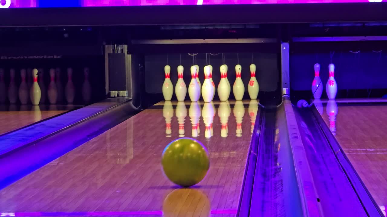 Fixed shot of bowling pins as the ball rolls down the lane and falls into the gutter