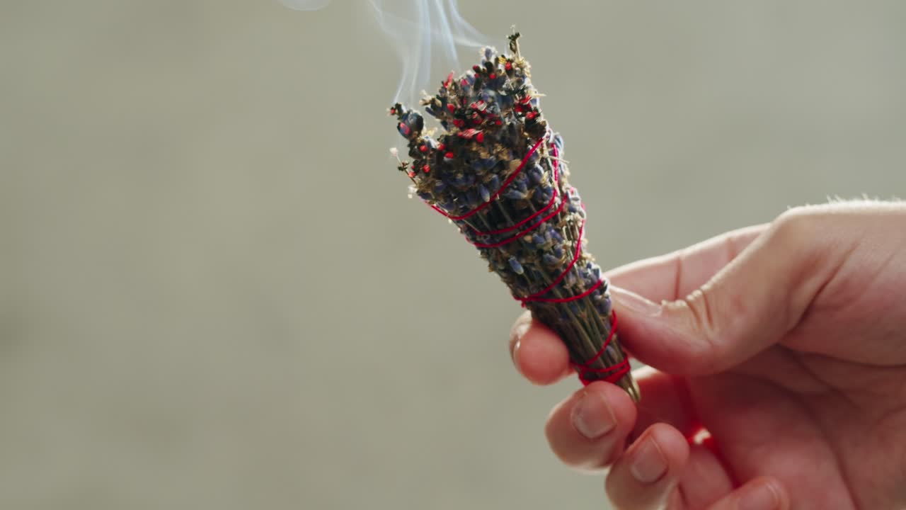 Person holding Palo Santo wood stick in hand, aromatic Palo Santo burning on black background, smoke spreading around, slow motion video clip, high quality 4k close up footage. High quality 4k footage