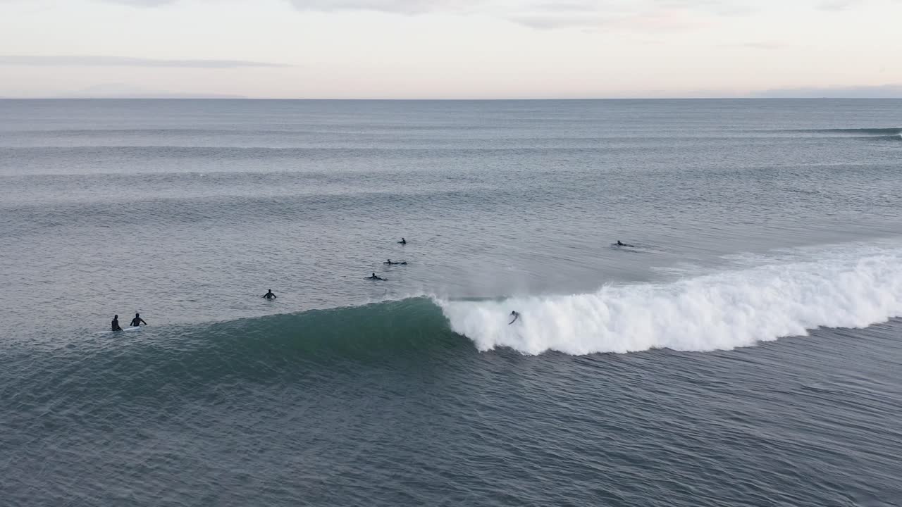 Surfista che prende l'onda dalla lineup viene preso dalla schiuma dell'onda, aereo.