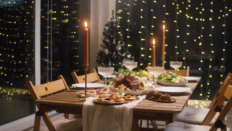 festive dinner at home, burning candles on dining table. celebrating new year, delicious dishes, cooked homemade food on plates. christmas party concept, family tradition.