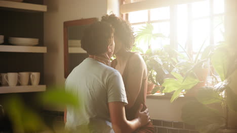 una pareja besándose en la cocina.