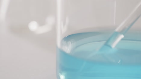 video of glass laboratory dish with blue liquid with copy space on white background