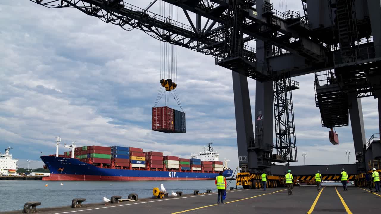 Wide-angle shot of a bustling port with workers and cranes moving containers, capturing the dynamic