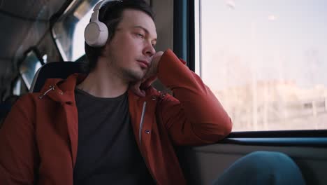 man in headphones travels by electric train with smartphone