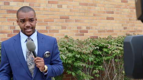 moving shot behind camera revealing young african american male news reporter making a live report