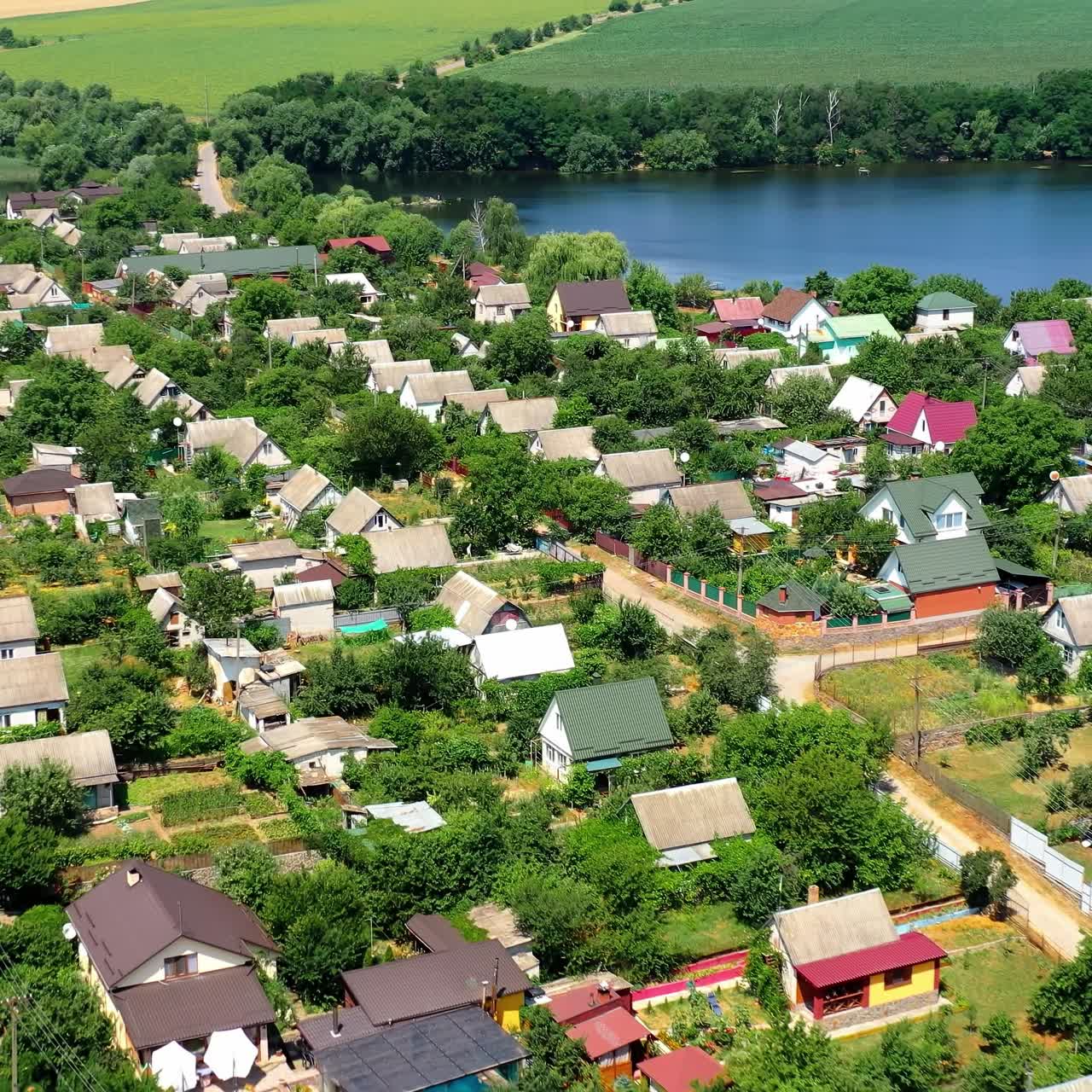 Countryside near the river. Flight over the roofs of village buildings on the background of picturesque nature. Amazing nature in rural place. Aerial view