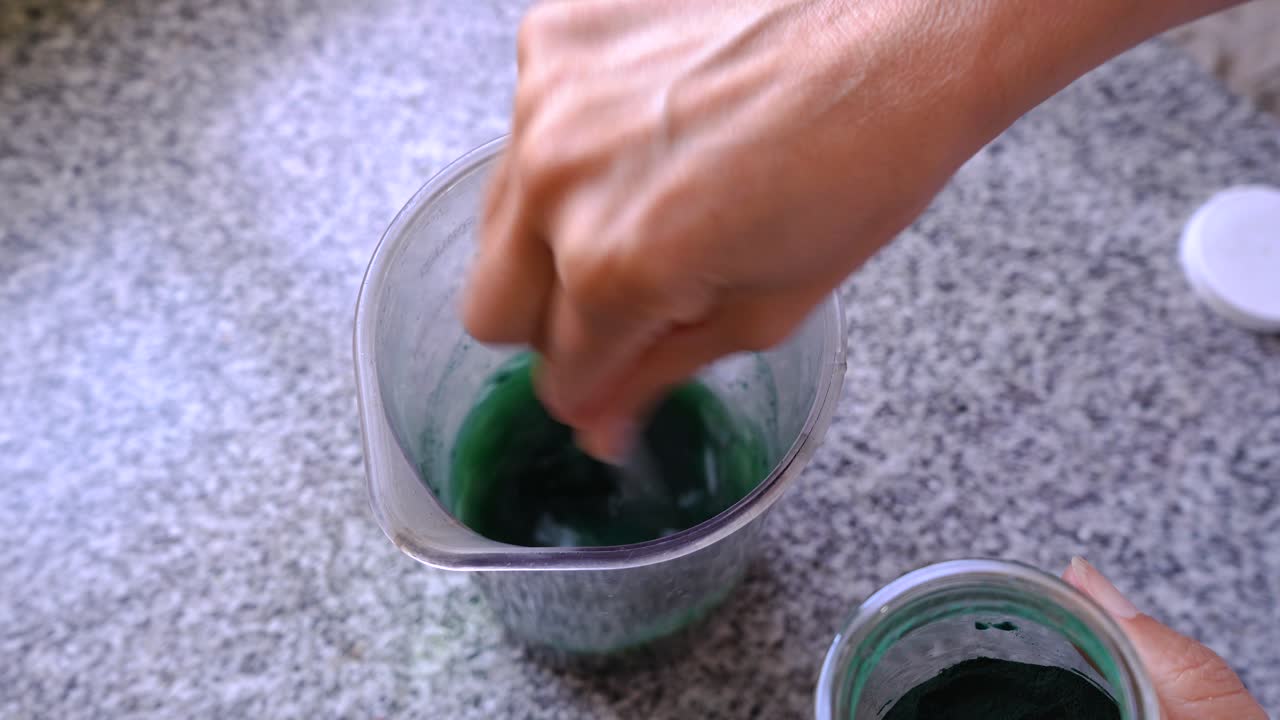 Aggiungere e mescolare un cucchiaino di polvere di spirulina a succo verde in una caraffa