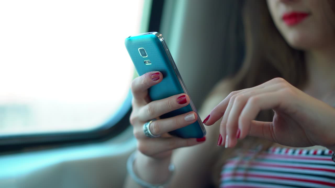 mujer esperando en el tren es un buen momento para hacer algo de trabajo en su dispositivo de teléfono, utilizando el teléfono inteligente para chequear su correo electrónico y escribir texto, mientras espera llegar a su estación de parada en milán