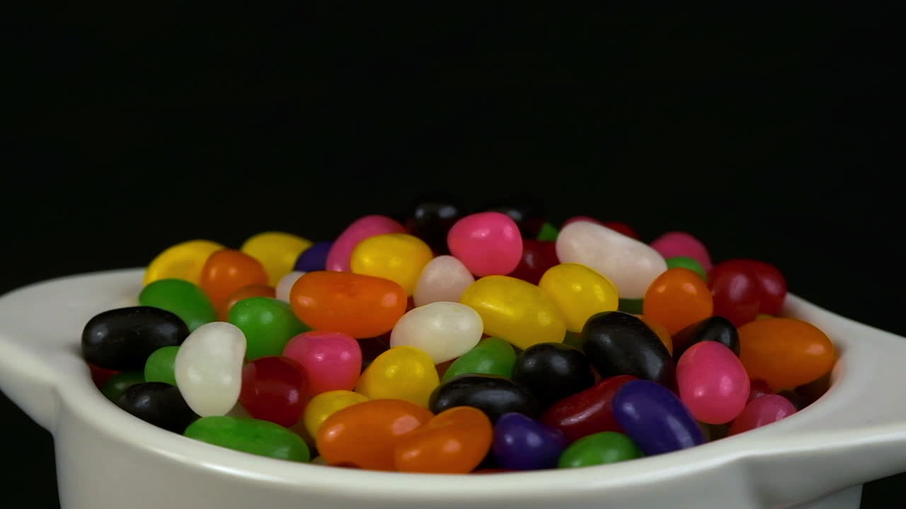 profundidad estrecha de campo: caramelos de jelly bean rotan en el cuenco en una habitación oscura