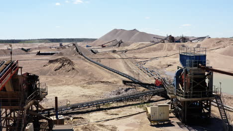 sand and gravel mine with piles of extracted materials, conveyor belts, and heavy machinery. drone shot