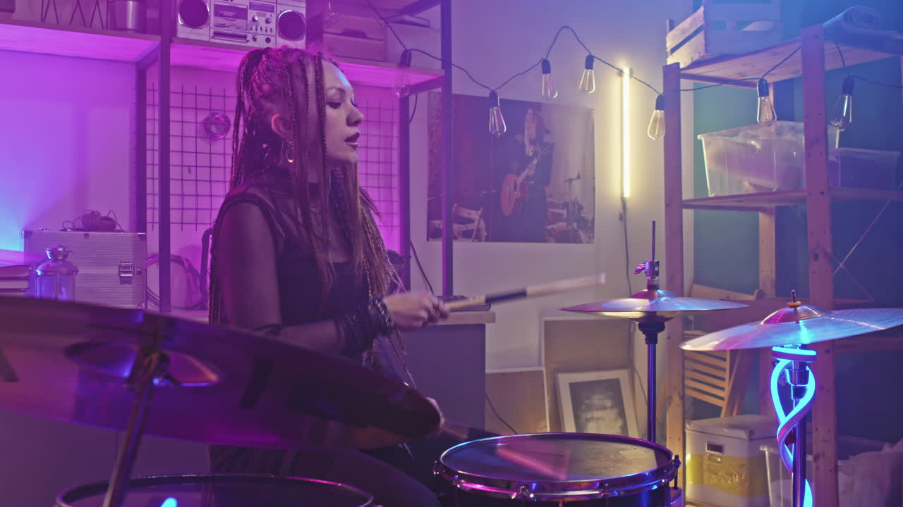 Ragazza rock con dreadlock che suona la batteria a un concerto