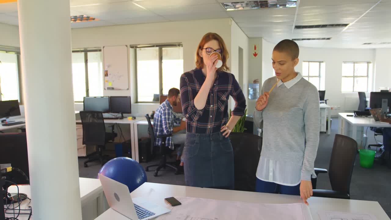 Giovani dirigenti donne caucasiche che discutono su un progetto in ufficio 4K.