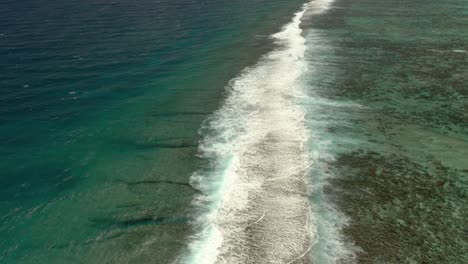 Aerial-view-of-the-sea-waves-breaking-over-the-barrier-reef-in-Mo'orea-island,-French-Polynesia