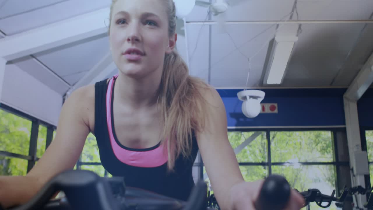 Woman cycling in gym, tapping right handle control, adjusting intensity, causing pulsing overlay UI