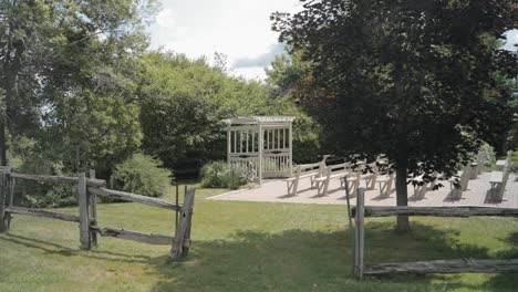 caminar a través de un césped a través de una valla de madera rodeada de árboles para revelar la pérgola de madera del lugar de celebración de la boda al aire libre en el centro de eventos y bodas de strathmere