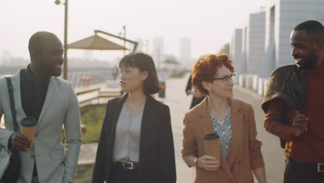 multiethnic business people walking and talking in street