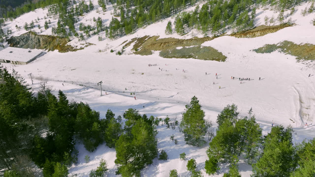 Vista aerea di piste da sci montane innevate con persone e paesaggio boschivo