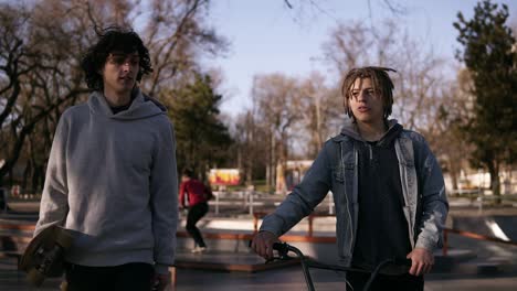 Dos-Amigos-Skater-Y-Bmx-Rider-Están-Caminando-Juntos-En-El-Parque-De-Patinaje-De-La-Ciudad