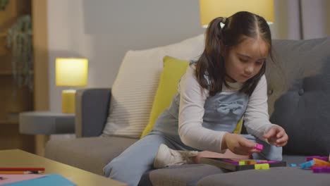 young girl on asd spectrum at home sitting on sofa solving shape puzzle 6