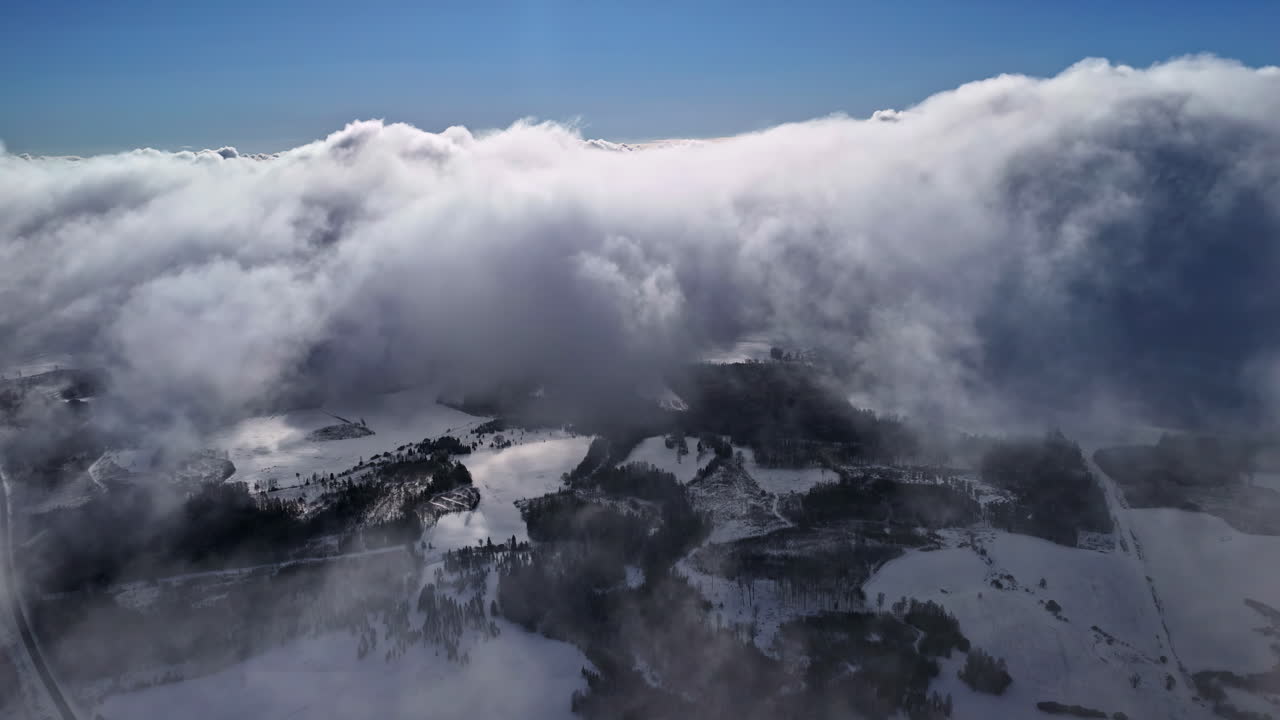 Drone flight through a thick cloud cover over a winter landscape