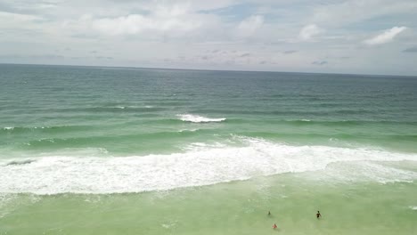 Aerial-View-Of-Beach-And-Ocean-Waves-With-Tourists-Enjoying-The-Water-In-Summer---drone-shot