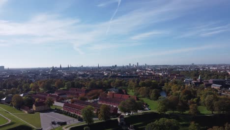 Splendid-Kastellet-fortress-with-its-perimeter-wall-and-moat-besides-the-red-houses-and-leafy-trees-on-a-summer-day-in-Copenhagen,-aerial-view