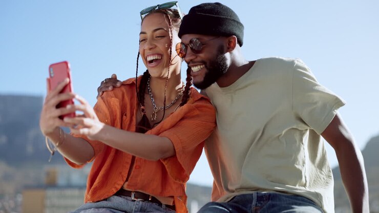 Coppia, affiatamento e selfie con telefono su edificio cittadino
