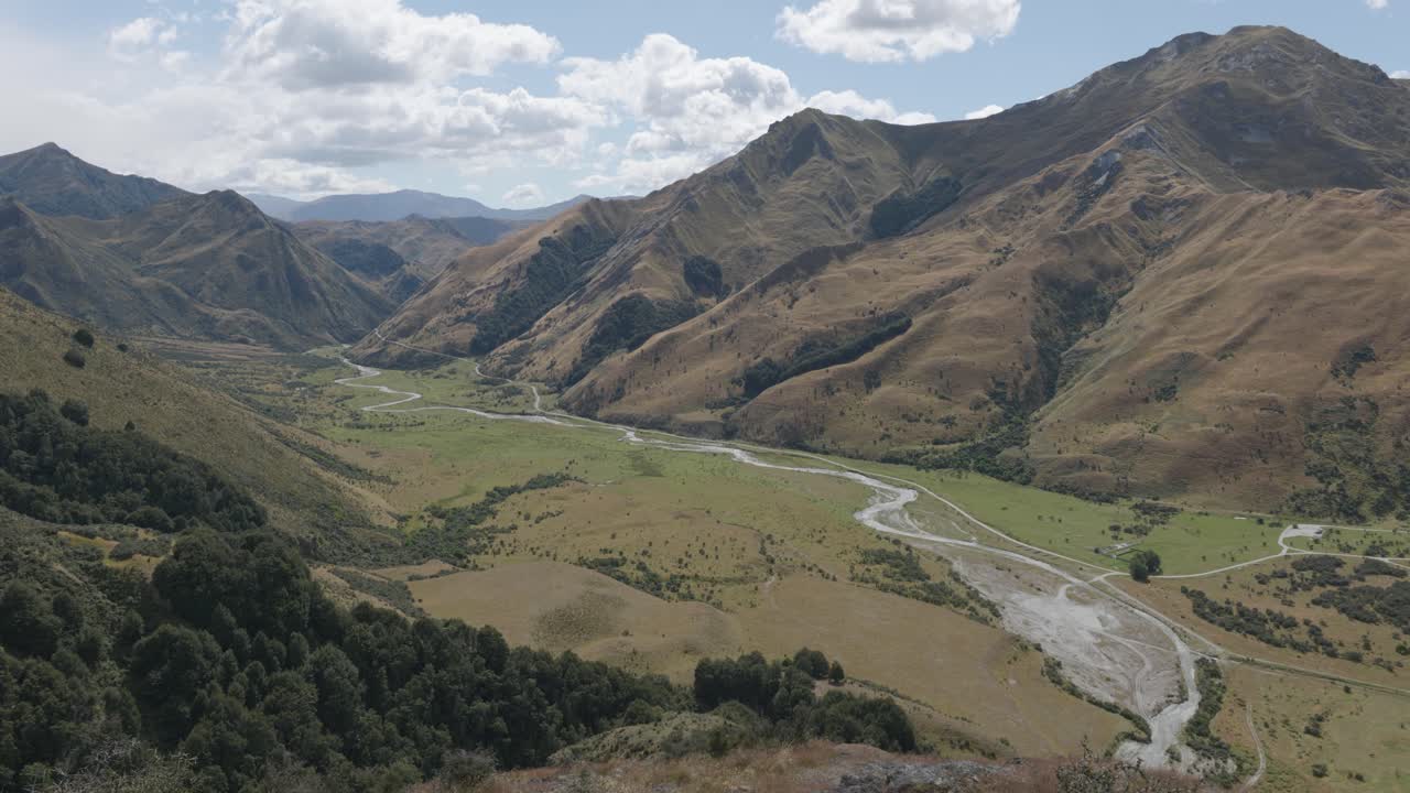 Wide view of river running through a valley between mountains on a sunny summer day at Moke Lake, Queenstown, New Zealand