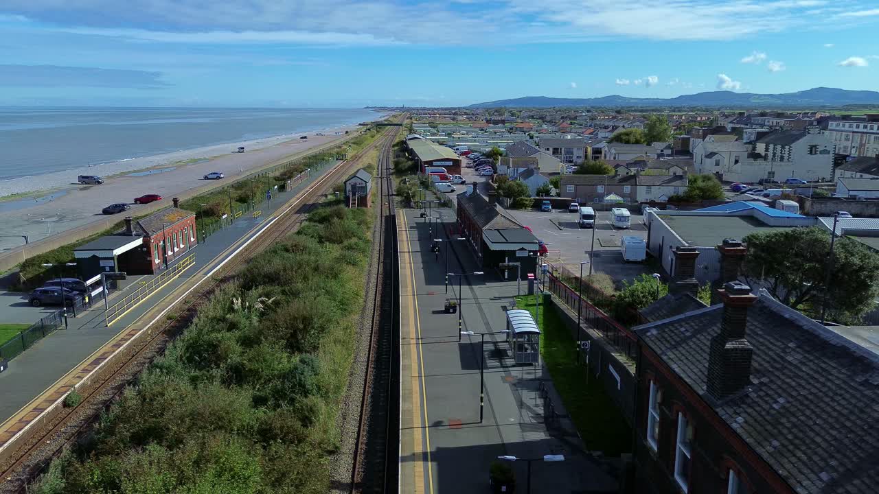 Pensarn beach aerial view flying over the town railway station and sunny welsh coastal promenade