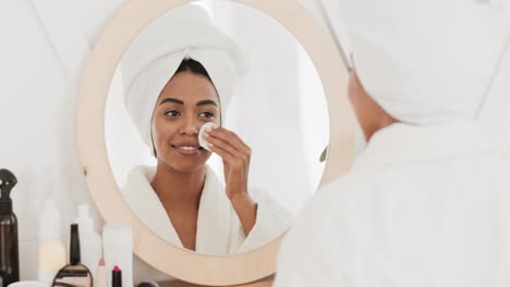 woman cleansing her face in bathroom