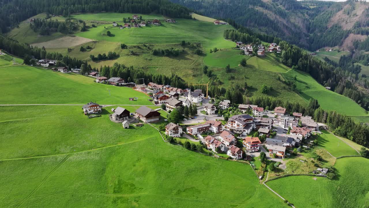 Drone glides left over Antermoia village in Italy, lush green summer hills, 4K
